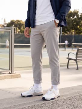 A refined athleisure outfit consisting of slim-fit heather grey joggers, a premium white crew-neck t-shirt, and a lightweight navy windbreaker.