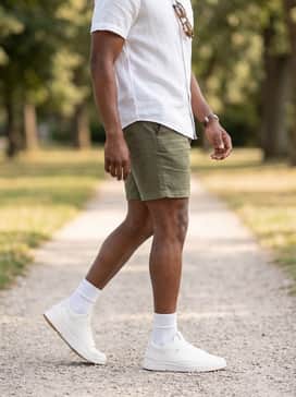 A summer-ready style with olive green linen shorts, a white short-sleeve linen button-down, and classic tortoiseshell sunglasses for a clean, breezy appearance.