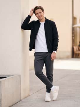 The Roger Clubhouse Ace – Tailored charcoal grey tech-fleece joggers, a high-quality white pima cotton t-shirt, and a sleek black bomber jacket for a modern, athleisure-inspired silhouette.