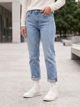 The Roger Clubhouse Mid – High-waisted light wash distressed straight-leg jeans paired with a tucked-in oversized cream turtleneck sweater.