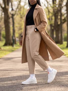Beige tailored trousers and a slim-fit black turtleneck sweater topped with a long trench coat for a sophisticated metropolitan look.