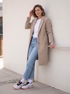 The Roger Pro Clay – Cuffed light-wash straight-leg jeans with a tucked-in premium white tee and a structured beige overcoat for a refined weekend aesthetic.