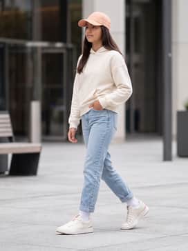 The Roger Youth – Light-wash slim-fit denim jeans paired with an oversized cream hoodie and a matching peach-toned baseball cap for a modern streetwear look.