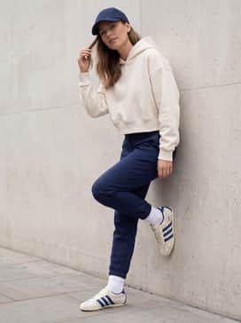Navy blue tailored joggers with a cropped white hoodie and a matching blue baseball cap for a cohesive and sporty urban look.
