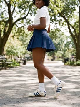 A pleated navy tennis skirt paired with a white polo shirt and white crew socks to lean into a 'preppy-sporty' aesthetic.
