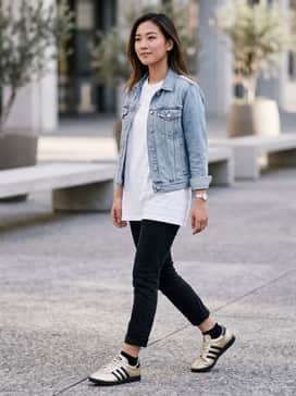 Slim-fit black cropped jeans paired with an oversized white graphic tee and a light-wash denim jacket for a classic, edgy street look.