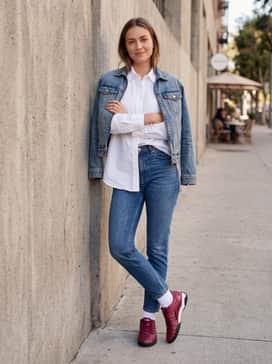Slim-fit tapered blue denim jeans with a crisp white oversized button-down shirt tucked in at the front for a smart-casual weekend vibe.
