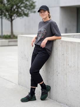 A casual urban outfit consisting of cropped black utility trousers, an oversized charcoal graphic t-shirt, and a minimalist black baseball cap for a balanced streetwear silhouette.