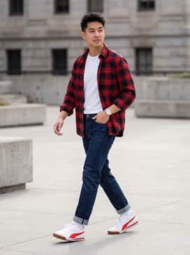 Slim-fit dark wash indigo jeans paired with a crisp white t-shirt and a red flannel shirt worn open to echo the shoe's accent color.