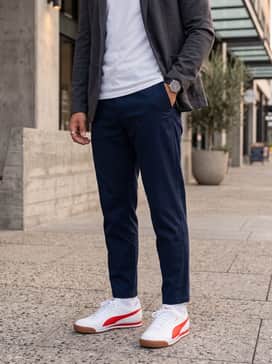 Navy blue tapered chinos combined with a light grey crewneck sweatshirt and a navy bomber jacket for a smart-casual city look.