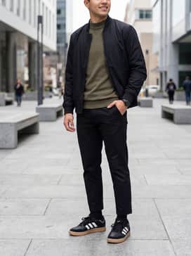 Slim-fit black chinos paired with a tucked-in olive green mock-neck shirt and a black bomber jacket to emphasize the shoe's sleek silhouette.