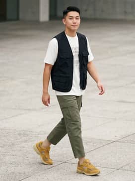Olive green ripstop cargo pants paired with a heavyweight white graphic t-shirt and a black utility vest for a rugged streetwear aesthetic.