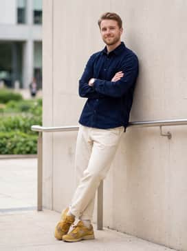 U2002dx – Relaxed-fit cream chinos worn with a tucked-in navy blue corduroy shirt for a smart-casual ensemble with a pop of earthy color.