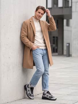 U2002r – Light-wash straight-leg vintage denim, a cream-colored mock-neck sweater, and a camel-colored long wool overcoat for a sophisticated 'dad-core' ensemble.