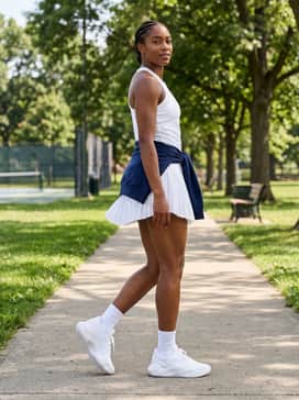 Ua Ace Low 2 – A white pleated tennis skirt and a fitted navy blue quarter-zip pullover for a classic, coordinated athletic look on or off the court.