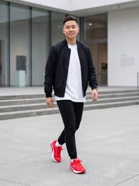 Black slim-fit joggers paired with an oversized white graphic tee and a black nylon bomber jacket for a sleek urban look.