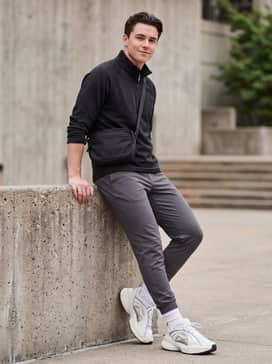 Slim-fit charcoal grey joggers matched with a black technical quarter-zip pullover and a sleek nylon crossbody bag for a functional sporty look.