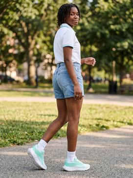 Ua Ascend Al – A bright summer outfit featuring light-wash denim shorts and a crisp white polo shirt with teal tipping on the collar to highlight the shoe's vibrant colorway.