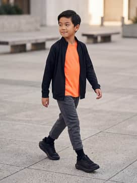 A pair of charcoal grey fleece joggers paired with a bright neon orange graphic t-shirt for a high-energy playground look.