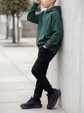 Slim-fit black tapered jeans combined with a forest green oversized hoodie for a cool, urban-inspired school outfit.