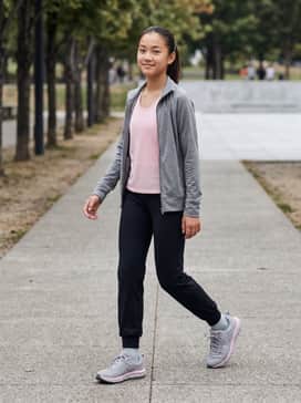 Ua Assert 10 Wide – High-performance black moisture-wicking leggings paired with a breathable light pink mesh tank top and a grey zip-up track jacket for a coordinated track-ready look.