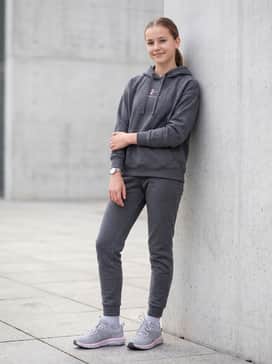 Ua Assert 10 Wide – Charcoal grey fleece joggers and a matching oversized hoodie with subtle pink embroidery to create a cohesive and comfortable travel or loungewear outfit.