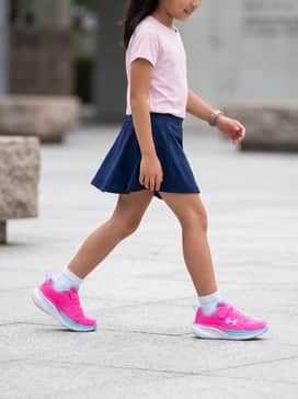 A navy blue moisture-wicking athletic skort paired with a light pink performance t-shirt and white ankle socks.