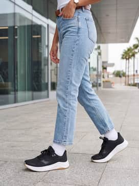 Cropped straight-leg light-wash jeans with a tucked-in white organic cotton tee and a structured olive utility jacket to balance the sporty silhouette with streetwear elements.