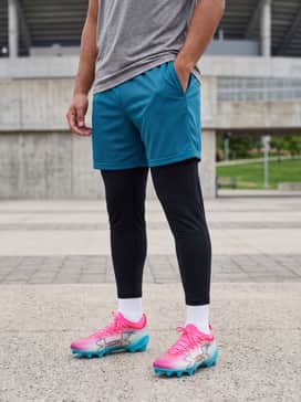 High-performance training gear including black compression tights, teal mesh athletic shorts, and a moisture-wicking technical tee.
