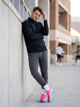 A sideline warm-up ensemble with tapered charcoal joggers, a sleek black quarter-zip performance top, and white crew-length athletic socks.