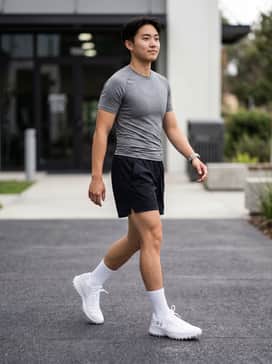 A performance-focused look featuring black moisture-wicking shorts, a grey compression tee, and white crew socks pulled mid-calf for a classic field-ready aesthetic.