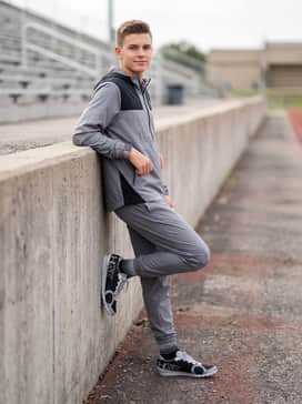 Performance-focused warm-up gear consisting of tapered athletic joggers and a lightweight half-zip windbreaker in a matching grey palette.