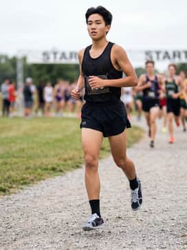 A professional racing look featuring split running shorts in matte black, a ventilated team singlet, and thin compression socks.