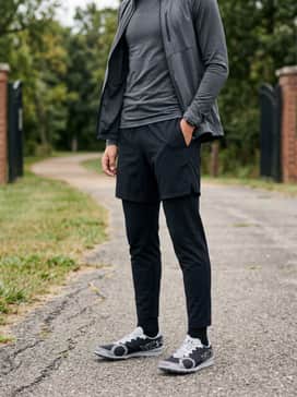Ua Brigade Xc 2 Spikeless – A sleek athleisure outfit consisting of charcoal tapered tech joggers, a fitted long-sleeve moisture-wicking top, and a lightweight nylon vest.