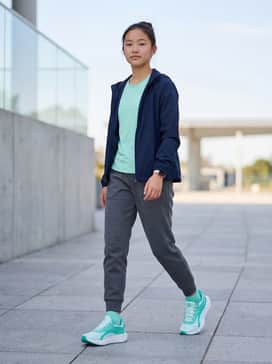 Ua Charged Ascend – A performance-ready look featuring charcoal grey tech-fleece joggers, a moisture-wicking mint green t-shirt to match the shoes, and a lightweight navy blue windbreaker.