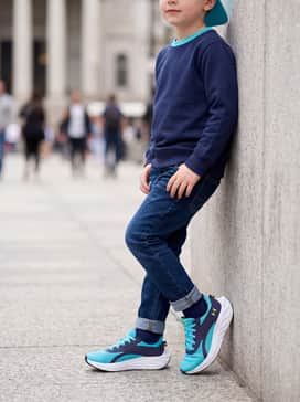 Ua Charged Ascend – Dark denim tapered jeans, a navy blue crewneck sweatshirt, and a bright cyan baseball cap to coordinate with the shoe's primary color.