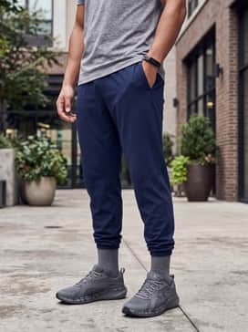 A sleek gym ensemble with tapered navy joggers, a light grey tech-fleece hoodie, and a matte black fitness tracker.