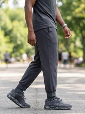 A coordinated training set with a black zip-up track jacket, matching track pants with side stripes, and silver-toned athletic accessories.