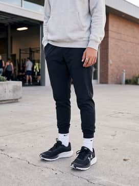 Ua Charged Chase Al – A trendy school outfit consisting of tapered black jogger pants, a layered heather grey hoodie, and a classic baseball cap for a street-ready aesthetic.