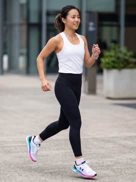 Ua Charged Chase – High-performance black compression leggings paired with a moisture-wicking white racerback tank top for a streamlined athletic silhouette.