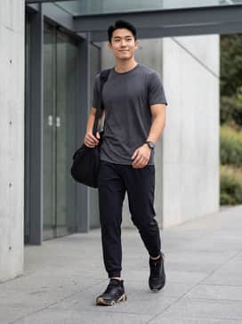 Ua Charged Commit Tr 5 – A performance-focused gym look featuring black moisture-wicking joggers, a charcoal compression T-shirt, and low-cut black athletic socks to maintain a sleek silhouette.