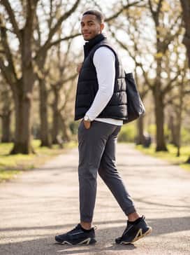 Ua Charged Commit Tr 5 – A comfortable travel or errand-ready look with charcoal grey tech fleece sweatpants, a crisp white long-sleeve performance top, and a black puffer vest for layered depth.