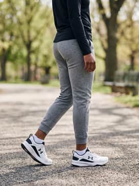 Ua Charged Edge – Grey tech-fleece sweatpants, a black quarter-zip pullover, and a minimalist black baseball cap for a coordinated and comfortable travel ensemble.