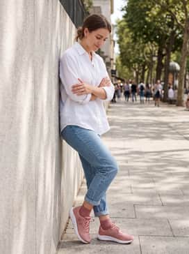 Ua Charged Pursuit 3 – Light-wash skinny jeans and a crisp white linen button-down shirt tucked in at the front, accessorized with rose-gold jewelry to complement the pink tones.