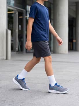 Ua Charged Pursuit 3 Big Logo – A navy blue performance moisture-wicking tee paired with charcoal grey athletic shorts and white crew socks for a classic gym class look.