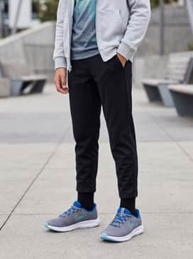 Ua Charged Pursuit 3 Big Logo – Black tapered joggers and a graphic t-shirt featuring blue tones, layered with a light grey zip-up hoodie for a comfortable school outfit.