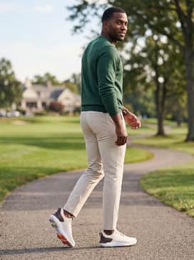 Ua Drive Pro Clone – A classic forest green lightweight knit sweater paired with light beige chino pants for a sophisticated post-round look at the clubhouse.