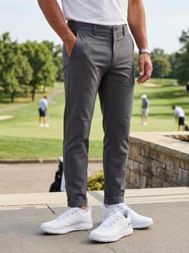 Ua Drive Pro Clone Spikeless – An elevated casual outfit consisting of slim-fit charcoal grey chinos, a light blue button-down oxford shirt worn untucked, and a silver-toned watch to match the shoe's logo.
