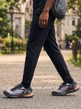 Relaxed-fit grey sweatpants with a fitted black long-sleeve performance shirt and a technical sling bag for functional everyday wear.