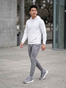 Style with slim-fit grey joggers and a white moisture-wicking hoodie for a high-end athleisure look.
